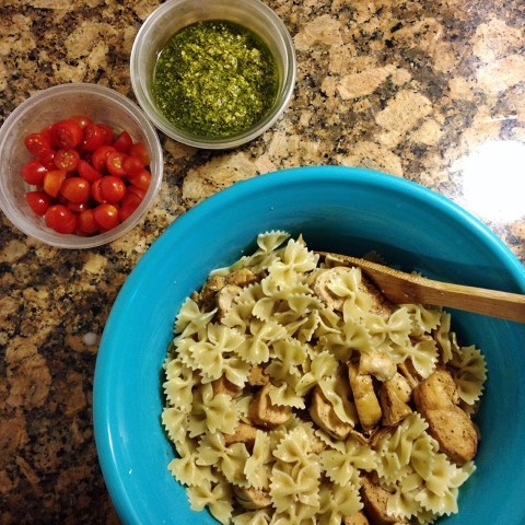 Top left corner: 1 cup grape tomatoes, halved and 1 cup pesto. Bottom right corner: cooked Farfalle pasta tossed with grilled chicken. 