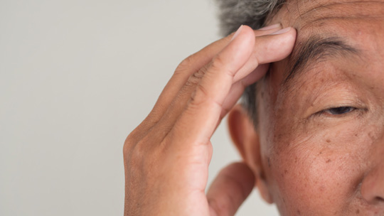 close-up of an elderly man holding his head to signify memory loss